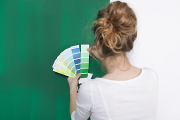 Image showing Woman with color plates in front of a green wall