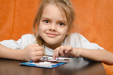 Image showing The girl at table tinkering sand applique