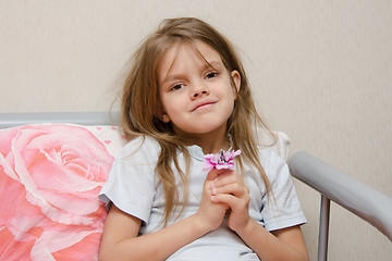 Image showing Five year old girl sitting in bed with a flower