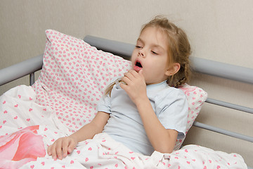 Image showing Diseased girl lying in bed coughing