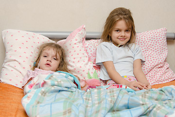 Image showing Two girls sick in bed with a thermometer