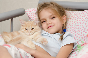 Image showing Portrait of the girl with a cat lying in bed