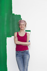 Image showing Woman with paint roller in front of wall