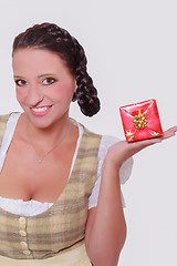 Image showing Young Bavarian woman in dirndl with a small gift on your palm.