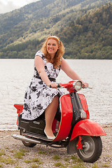 Image showing Obese redhead beauty on a red scooter