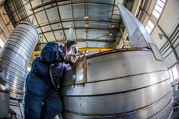 Image showing Man welding with reflection of sparks on visor. Hard job. 