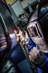 Image showing Man welding with reflection of sparks on visor. Hard job. 