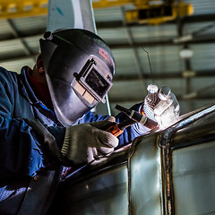 Image showing Man welding with reflection of sparks on visor. Hard job. 