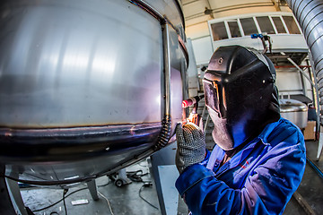 Image showing Man welding with reflection of sparks on visor. Hard job. 