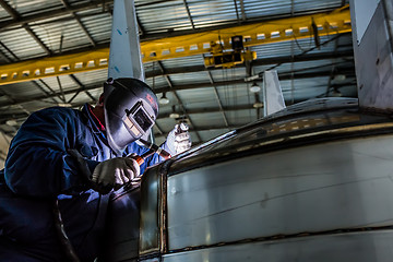 Image showing Man welding with reflection of sparks on visor. Hard job. 