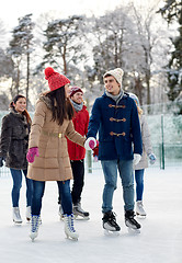 Image showing happy friends ice skating on rink outdoors