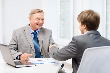 Image showing older man and young man shaking hands in office