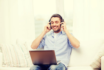 Image showing smiling man with laptop and headphones at home