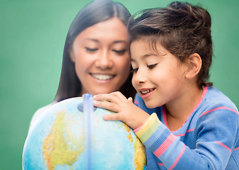 Image showing happy teacher and little school girl with globe