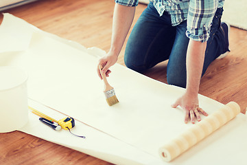 Image showing closeup of male hands smearing wallpaper with glue