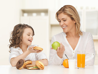 Image showing happy mother and daughter eating breakfast