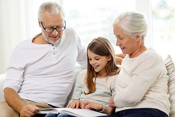 Image showing smiling family with book at home