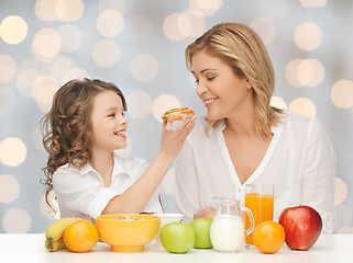 Image showing happy mother and daughter eating breakfast