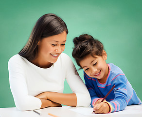 Image showing happy teacher and little school girl drawing