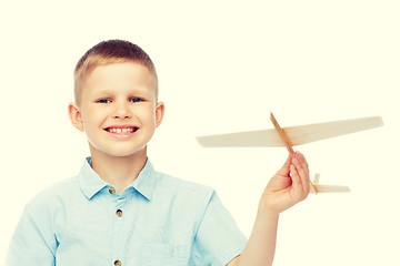 Image showing smiling little boy holding a wooden airplane model