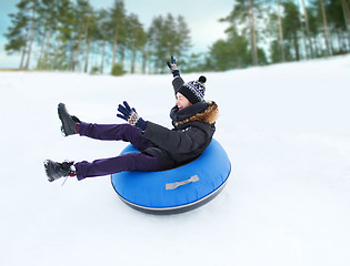 Image showing happy young man sliding down on snow tube