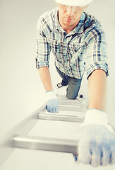 Image showing man in helmet and gloves climbing ladder