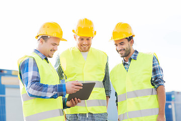 Image showing smiling builders in hardhats with tablet pc