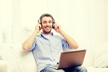 Image showing smiling man with laptop and headphones at home