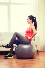 Image showing smiling redhead girl exercising with fitness ball