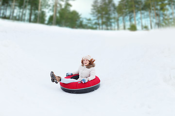 Image showing happy teenage girl sliding down on snow tube