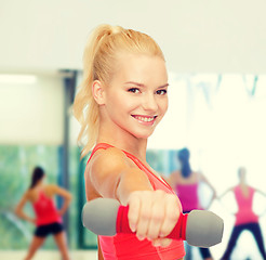 Image showing smiling beautiful sporty woman with dumbbell