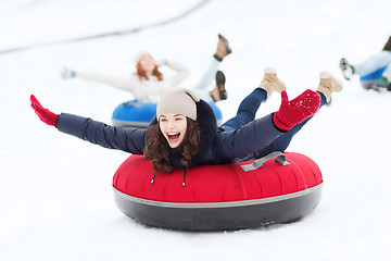 Image showing group of happy friends sliding down on snow tubes