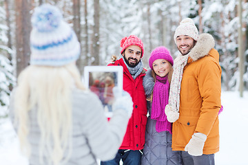 Image showing smiling friends with tablet pc in winter forest