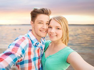 Image showing smiling couple with smartphone on summer beach