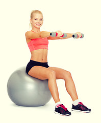 Image showing woman with dumbbells sitting on fitness ball