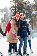 Image showing happy friends ice skating on rink outdoors