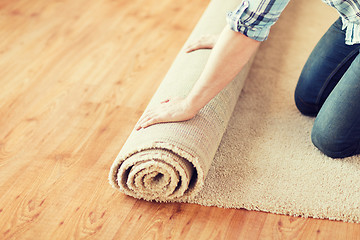 Image showing close up of male hands unrolling carpet