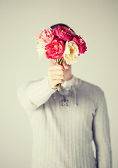 Image showing man covering his face with bouquet of flowers