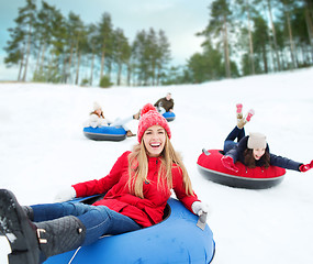 Image showing group of happy friends sliding down on snow tubes