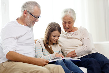 Image showing smiling family with book at home