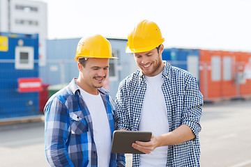 Image showing smiling builders in hardhats with tablet pc