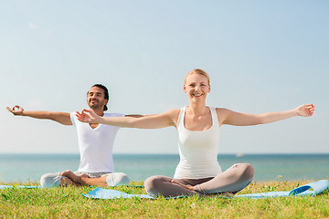 Image showing smiling couple making yoga exercises outdoors