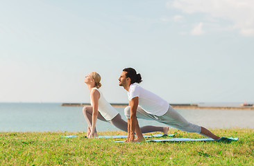 Image showing smiling couple making yoga exercises outdoors