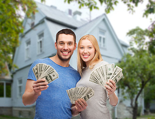 Image showing smiling couple showing money over house background