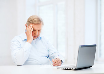 Image showing old man filling a form at home