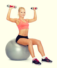 Image showing woman with dumbbells sitting on fitness ball