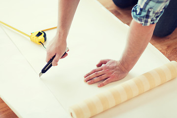 Image showing close up of male hands cutting wallpaper