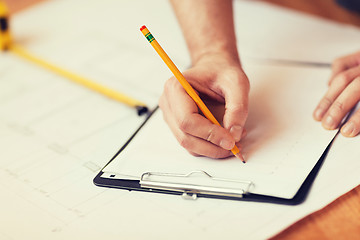 Image showing close up of male hands writing in clipboard