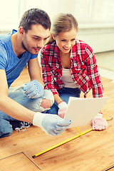 Image showing smiling couple measuring wood flooring