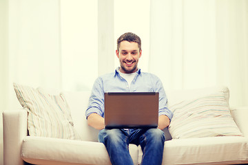 Image showing smiling man working with laptop at home